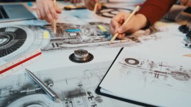 Ayrıntılı teknik çizimler ve mühendislik şemalarının yer aldığı bir çalışma alanı. Eller aktif olarak tasarım sürecinde, yaratıcılık ve hassasiyet gösteriyorlar. SACTR