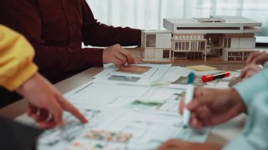 Bir mimarlık stüdyosunda çalışan bireyler, modern tasarım projelerinde işbirliği yapıyor, planlar üzerinde tartışıyor ve modelleri değerlendirirken yaratıcılığı ve yeniliği teşvik ediyorlar. SACTR