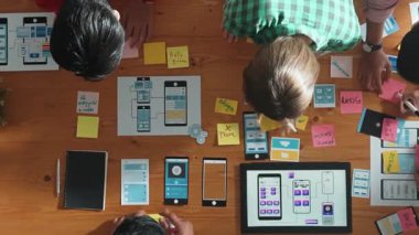 Mobil telefon arayüzü için Ux Ui tasarımı planlarken iş adamlarının yapışkan notlar üzerine yazı yazma fikrine tepeden aşağı bakış açısı. Bir grup yaratıcı tasarımcı kablo prototip tasarımı üzerinde çalışıyor. Cemaat.