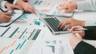 Profesyoneller modern ofis ortamında işbirliği yaparak, grafikleri ve grafikleri olan bir dizüstü bilgisayardaki verileri analiz ederek, dinamik bir atmosferde takım çalışması ve stratejik planlamayı vurgularlar. SACTR