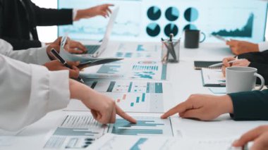 Çeşitli profesyonellerden oluşan bir grup, modern bir ofis ortamında veri analizi toplantısına katılıyor, çizelge ve dizüstü bilgisayarlarla işbirliği ve takım çalışması sergiliyor. SACTR