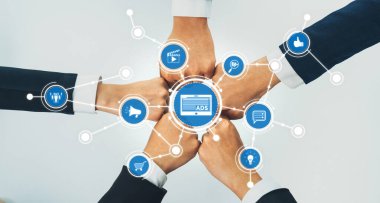 Bu resim, bir iş bağlamında takım çalışmasını, ellerin bir araya gelip çeşitli reklam ve pazarlama sembolleri aracılığıyla işbirlikçi bir ağda bir araya gelişini gösteriyor. Dostluk