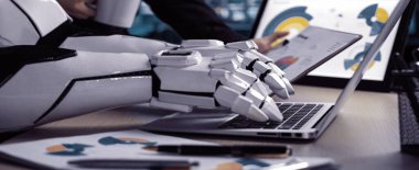 Bir robotik kol, bir iş ortamının ortasında bir dizüstü bilgisayarda çalışır, modern bir ofiste teknoloji ve verimliliğin birleşimini temsil eder. Noogenesis