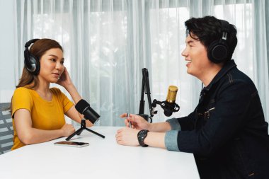 Gülümseyen radyo etkili sunucusu kulaklık takıyor kadın konuşmacı ile röportaj yapıyor sosyal medya internet sitesinden dinleyicilere bilgi paylaşıyor stüdyo kaydında sabah canlı yayın kanalı. İnfobahn.