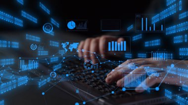 Eller, dijital evreni ve analitiği modern bir çalışma alanında temsil eden veri ve grafiklerin fütüristik görselleştirilmesiyle çevrili bir dizüstü bilgisayarda yazı yazıyor. Xenic