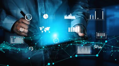 Yüksek teknolojili bir ortamda finansal performans ve pazar sezgilerini gösteren grafikler ve grafiklerle çevrili bir tablet üzerindeki dijital verileri analiz eden bir profesyonel. Xenic