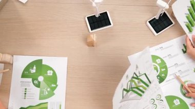 Eko evi projesini yel değirmeni tasarım modeli ve karbon ayak izini azaltmak için yeşil enerji kullanım grafiği ile toplantı masasında tartışan harika bir iş ekibi. Dünyayı kurtarın. Eline odaklan. Tanımlama.