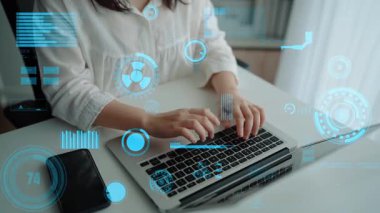 Yaratıcı bir profesyonel, teknoloji ve veri analizini temsil eden dijital arayüz elementleriyle çevrili modern bir çalışma alanında dizüstü bilgisayarla meşgul olur. Xenic