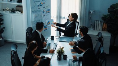 Üst düzey iş adamı görüşü beyaz tahtaya işaret ederken yönetici yönetici de sunumu dinliyor. Yetenekli yatırımcılar soru sormak için el kaldırdı. Akıllı ekip birlikte çalışıyor. Müdürlük.