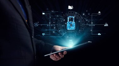 Bir işadamı, modern teknolojide veri koruması ve siber güvenliğin önemini temsil eden güvenlik simgelerini ve dijital kilidi gösteren bir tabletle etkileşime giriyor. Dörtgen