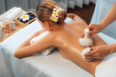 Sıcak bitkisel top spa masaj vücut tedavisi, masör kadın vücuduna nazikçe şifalı bitki torbası bastırıyor. Aromaterapi dinlenme sükuneti ve sükuneti kaplıca salonundaki atmosferi aydınlatıyor. Sessiz.