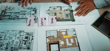 Canlı bir çalışma alanı, bir masanın üzerinde mimari planlar ve tasarım konseptleri sergiliyor. Renkli post-it notları profesyoneller arasındaki fikirleri ve yaratıcılığı vurgular. SACTR