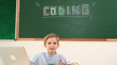 Kameraya karatahta ile bakarken elektronik tahtada çalışan zeki bir öğrenci. Çocuk, kodlama mühendisliği ve yapay zeka kullanarak programlama sistemine hazırlanırken ana tahtayı tamir ediyor. Pedagoji.