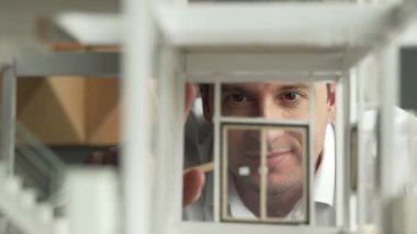 Kafkasyalı mimar mühendisinin yakın çekimi ev inşaatını denetlemek ve bina malzemelerini kontrol etmek. Proje yöneticisi modele dikkatlice bakarken kalemi işaret ediyor. Yönlendirici.