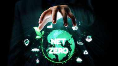 Bu çarpıcı görüntü, net sıfır emisyon ve sürdürülebilir uygulamalara acil odaklanmayı sembolize eden yeşil elementler ve simgelerle dolu canlı bir küreye uzanan bir eli temsil ediyor. Dörtgen