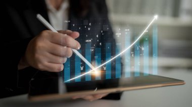 Bir iş adamı, şirket ortamında teknolojik gelişmeleri ve modern veri görselleştirme yöntemlerini vurgulayan bir tablet kullanarak finansal analize girişir. Etki
