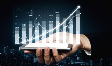 Akıllı telefonu tutan bir elin yakın plan görüntüsü, yükselen büyüme ile birlikte finansal tabloyu gösteren, yatırım başarısını ve veri analizini sembolize eden. Etki