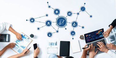 Verilerin grafik ve grafikler yoluyla analizini gösteren, modern stratejileri ve takım çalışmasını bir konferans ortamında yansıtan işbirlikçi bir iş toplantısının yüksek açılı bir görüşü. Dostluk