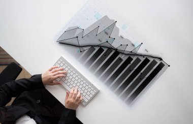 Bir iş adamı, finansal performans ve eğilimleri temsil eden grafikler ve grafiklerle etkileşim kurmak için bir klavye kullanarak veri analizi yapar. Etki