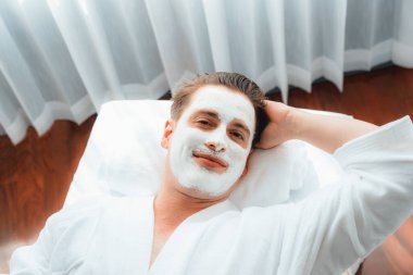 Kaplıca salonunun sakin atmosferi, insan müşterisi modern gün ışığında lüks yüz kremi masajıyla kendini yenileme zevkine kapılıyor. Yüz bakımı ve güzellik konsepti. Sessiz.