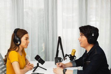 Gülümseyen radyo etkili sunucusu kulaklık takıyor kadın konuşmacı ile röportaj yapıyor sosyal medya internet sitesinden dinleyicilere bilgi paylaşıyor stüdyo kaydında sabah canlı yayın kanalı. İnfobahn.