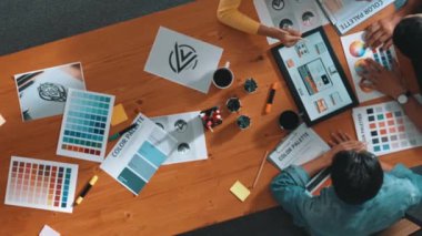 Proje yöneticisi renk paletleri seçerken tasarımcının tablete baktığı yukarıdan aşağıya hava görüntüsü. Profesyonel grafik tasarımının en üst görüntüsü ve logoya bakın. Yetenekli ekip grafikleri seçiyor. Sempozyum.