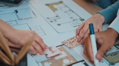 Canlı bir çalışma alanı, ellerin detaylı kat planları çizdiği, tasarım gelişiminde yaratıcılık ve takım çalışması sergilediği işbirlikçi bir mimari planlama oturumunu yakalar. SACTR