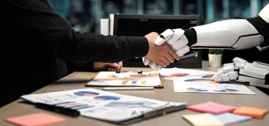 İnsan eli, modern bir ofiste ortaklığı temsil eden robotik bir elle titrer. Çizelgeler ve kağıtlar gibi görsel öğeler yenilik ve işbirliği temalarını vurgular. Noogenesis