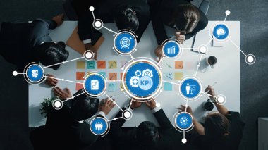 Çeşitli bir iş ekibi, modern bir masa etrafında anahtar performans göstergelerini analiz ederek işbirliği yapıyor. Parlak, dinamik bir çalışma alanında görsel araçlar ve teknolojiden yararlanırlar. Dostluk