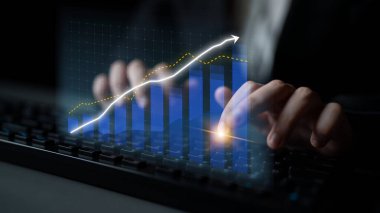 Bir klavyeye odaklanmış profesyonel tipler, dijital grafiklerde ise modern iş uygulamaları ve veri analizlerini yansıtan artan finansal eğilimler görülüyor. Etki