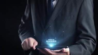Bir işadamı, modern bir kurumsal ortamda çeşitli iletişim yöntemlerini temsil eden dijital temas simgelerini gösteren bir akıllı telefon tutuyor. Dörtgen