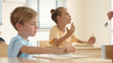 Beyaz bir çocuk ödevlerini yaparken ve açıklama dinlerken güzel bir öğretmen sınavı açıklıyor. Sınıfta not alırken ya da kağıda cevap yazarken öğretmenine bakan sevimli bir çocuk. Pedagoji.