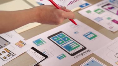 Girişimci şirket çalışanının el odaklı hali ofis çalışma alanındaki akıllı yöneticiye mobil uygulama için kullanıcı arayüzü prototipi sunar. UX UI tasarımcısı kağıt üzerinde simge tasarımının işlevini açıklıyor. Sinerjik