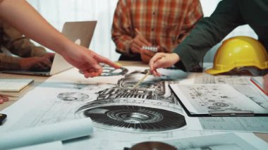 Değişik bir ekibin mühendislik tasarımları ve teknik çizimler hakkında detaylı bir tartışmaya girdiği dinamik bir ofis sahnesi, işbirliği ve yeniliği vurguluyor. SACTR