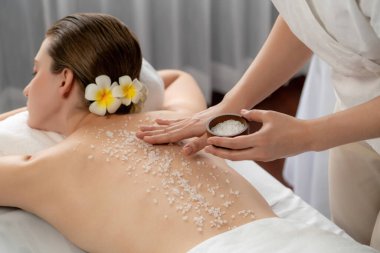 Lüks spa salonlarında sıcak mum ışığında cilt bakımı yaptıran kadın müşteri. Sağlık Spa vücut fırçasında tuz temizleme güzellik tedavisi. Sessiz.