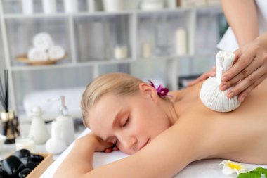 Sıcak bitkisel top spa masaj vücut tedavisi, masör kadın vücuduna nazikçe şifalı bitki torbası bastırıyor. Aromaterapi dinlenme sükuneti ve sükuneti kaplıca salonundaki atmosferi aydınlatıyor. Sessiz.