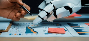 Bir insan eli ve robot el iş haritaları üzerinde birlikte çalışır, veri eğilimlerini analiz eder ve iş yerindeki teknoloji ile insan yaratıcılığının kaynaşmasını gösterir. Noogenesis