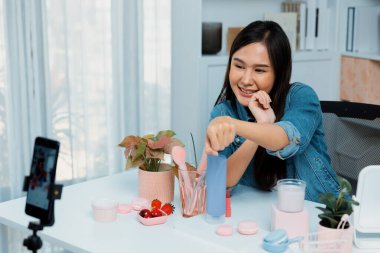 Genç, güzel Asyalı kozmetik makyaj ruju matte pastel rengini modern odadaki sosyal medyada kol testi tanıtımında en çok satanlar listesinde gösteriyor. Taktik.