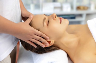 Kafkasyalı kadın stres önleyici kafa masajından ve lüks tatil beldesi ya da otel spa salonundaki modern ışık ortamında yüz güzelliği eğlencelerini şımartmaktan hoşlanıyor. Sessiz.