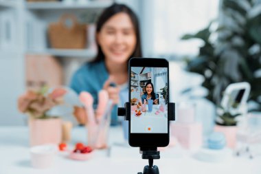 Genç ve güzel Asyalı bir kızın nemlendirici vücut kremi ürününü inceleyerek sosyal medyada koluyla en çok satanlar listesine giren canlı bir cilt testi yaptığı seçmeli bir odak telefonu. Taktik.