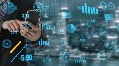 Bir işadamı dijital çizelgeler ve grafiklerle çevrili akıllı telefondaki finansal verileri analiz eder. Bu görüntü, modern bir ortamda piyasa eğilimlerini ve stratejik iş büyümesini temsil etmektedir. Xenic