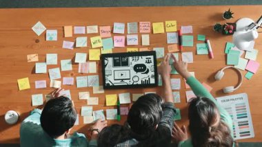 Toplantı masasında renk paletleriyle birlikte yapışkan notlar kullanarak yaratıcı tasarımcının beyin fırtınası fikrinin üst görüntüsü. Akıllı takımın hava görüntüsü tabletten simge grafiği seçiyor. Sempozyum.