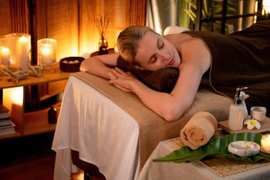 Beyaz kadın müşteri stres önleyici spa masajının keyfini çıkarıyor ve lüks otel ya da otelde sıcak mum ışığında güzellik teniyle eğleniyor. Sessiz.