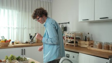 Mutlu baba yemek pişirirken müziğe geçiyor ve modern mutfakta öğle yemeği hazırlıyor. Aktif baba, sebze ve mutfak gereçleri ile çevrili sağlıklı yemek ya da salata yaparken şarkıyla dans ediyor. Pedagoji.