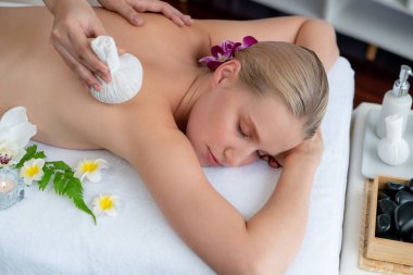 Sıcak bitkisel top spa masaj vücut tedavisi, masör kadın vücuduna nazikçe şifalı bitki torbası bastırıyor. Aromaterapi dinlenme sükuneti ve sükuneti kaplıca salonundaki atmosferi aydınlatıyor. Sessiz.