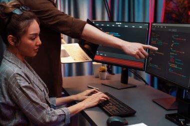 Modern ofisteki neon ışık odasında bilgi ağını gösteren dizüstü bilgisayarla iki ekranda veri çalıştıran akıllı web sitesi geliştirme kodlayıcı sistemini tartışan IT geliştiricilerinin ciddiyeti. İnfobahn.