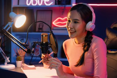 Geceleri podcast 'te olumlu konuşmalar yapan, pembe neon ışıklı modern stüdyoda sunum için dizüstü bilgisayar kullanan, gülümseyen, genç, güzel Asyalı bir etkileyiciydi. Taktik.