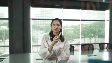 Profesyonel genç ve stresli iş kadını pazarlama sorunlarını çözmenin yollarını düşünürken aynı zamanda renkli yapışkan notlarla ve pazarlama fikriyle cam tahtada duruyor. Yönlendirici.