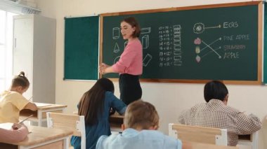 Profesyonel mutlu öğretmen sınıfta oturan çeşitli mutlu öğrencilerden not defteri toplar. Kafkas hocası sınıfta dolaşırken çocukların ödevlerini topluyor. Eğitim konsepti. Pedagoji.