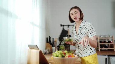 Mutlu genç anne mutfakta dururken salata kasesine sebze koydu. Çekici beyaz bir kadın yemek pişirmekten ve sabah taze organik yemek yapmaktan ya da ev yemeği yapmaktan zevk alır. Pedagoji.